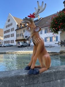 Rentier Rudolf sitzt auf dem Dorfbrunnen und wartet auf den Weihnachtsmann